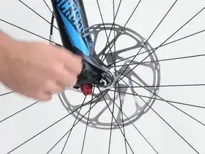 Slide the axle in with the quick-release lever opened. As soon as the axle thread engages with the thread of the opposite side, close it by turning clockwise.