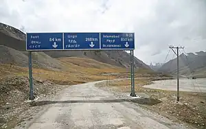 Road signs on Karakoram Highway near the Pakistan-China border featuring Pakistani destination names in Latin, Chinese, and Cyrillic script