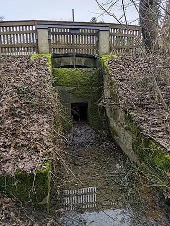 Kanal-Grundablass als Kombination von Grundablass-Schütz (Auslass unten, Schieber hinter Mauer und bewegt mit Zahnstangen-Gewinde) und Hochwasser-Überfallwehr (Kante oben)