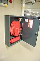 Wandhydrant, Schlauch angeschlossen, wasserführend.