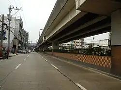 Section of the Avenue in Caloocan. The viaduct of the LRT Line 1 can be seen above. A station of the LRT Line 1 can be seen in the distance.