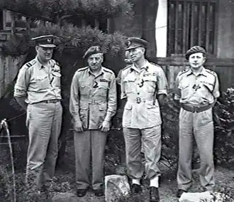 Full-length outdoor portrait of four men in light-coloured military uniforms