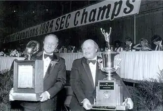Two men holding trophies