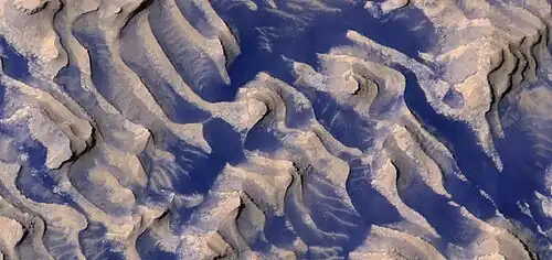 Close, color view of layers and dark dust on floor of Danielson Crater, as seen by HiRISE under HiWish program. Boulders are visible in the image.