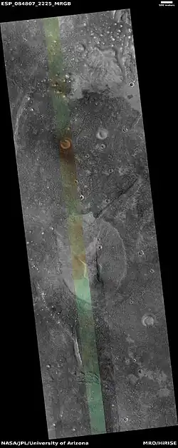 Wide view of mud volcano, as seen by HiRISE. The light-toned spots are the mud volcanoes. They have a different tone than the surroundings because they contain material brought up from depth. These structures may be useful to explore for remains of past life since they contain samples that would have been protected from the strong radiation at the surface. The colored strip is about 1 km wide.