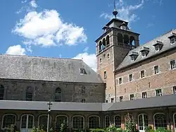Le cloître de l'abbaye de Leffe et, à son angle, la tour clocher (photographie moderne).