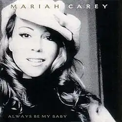 A black-and-white photo of Carey smiling from the song's remix video, sporting a long wavy hairstyle and wearing a large hat.