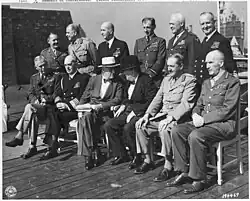 Black and white photograph of two rows of men. Six men each are seated and standing in varying attire