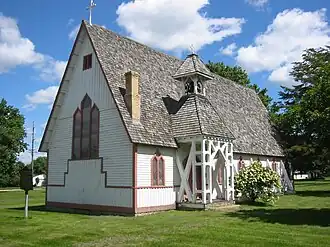 A small wooden church with a steeply pitched roof and an elaborate side entry