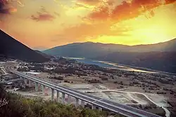 A sunset with mountains and a highway as a focus of the image