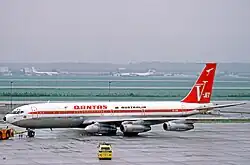 Qantas Boeing 707-338C convertible passenger/freight aircraft carrying a spare engine under its wing root at Frankfurt Airport in 1972