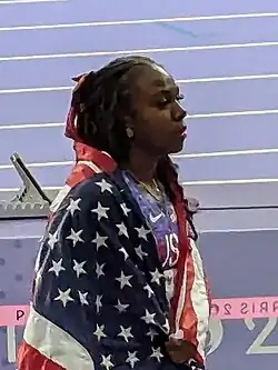 Mason walking off-track with a United States flag wrapped around her shoulders.