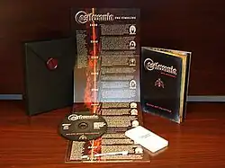 Photograph of a collection of items: a black cardboard case about 5 inches by 7 inces with crimson plastic seal with the Castlevania emblem, a black music CD, a small fold-out vertical poster with a timeline extending from top to bottom, a small white plastic stylus pen for touchscreens, a small white plastic game case, and a black pocket-sized book with the Castlevania logo and emblem on the front cover.