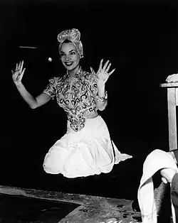 A smiling Miranda, in costume, holds up her hands after leaving her prints outside Grauman's Chinese Theatre.