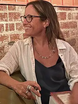 author sitting on couch holding a book and pen