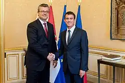 Valls is shaking hands with Orešković in front of their respective country's flags.