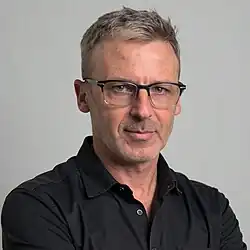 close-up of Daniel Landau wearing a black shirt, looking directly at camera with slight smile
