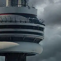 Drake sits on the CN Tower with a cloudy sky on the background.