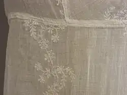 Detail of white embroidery in a floral design on a white muslin dress, circa 1805