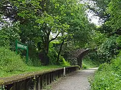 The Camel Trail passing through the disused partially-restored Dunmere Halt, under a bridge that carries road traffic through the hamlett