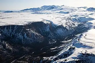 A rocky canyon cut into a snow-covered plateau