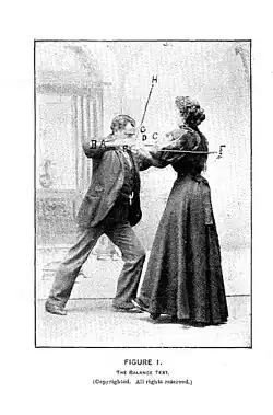 Hurst holds the cue out in front of her chest with her elbows bent with a person pushing against her.