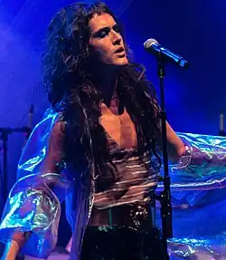 Catto singing on stage and photographed from their front right corner