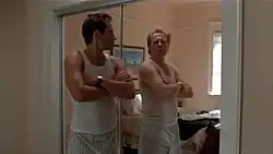 A man looks at himself in a mirror, seeing a completely different man's reflection.