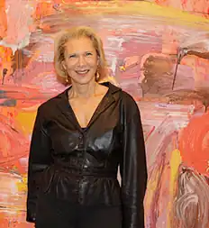 Francine Tint standing next to a large abstract painting titled "RED"