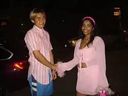 Male on the left handshakes a female on the right. It's dark outside