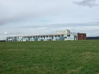 A photo of a long building taken from a field nearby