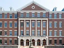 A large Georgian-era style building complete in red brick, classical columns and a statue in front