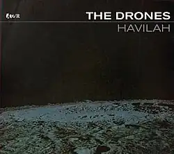 The bottom third is a black-and-white shot of a lunar landscape, a small crater is in the foreground. A larger crater is near the horizon. The rest of the cover is black except for the lettering near the top. At left is the record label's logo of four letters. The artist's name in larger white block capitals is at top right. Below is a light blue line all the way across the cover. Under the line, on the right, is the title in grey block capitals.