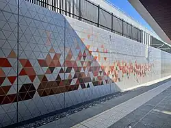 Concrete retaining wall with orange-red coloured triangles inscribed on it