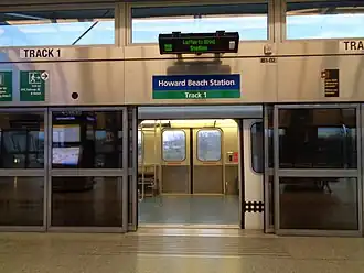 A glass and metal platform screen door at the AirTrain JFK's Howard Beach station