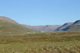 A grassy plain with stubby mountains rising on either side