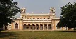 Single-story colonnaded façade with grass and trees in front
