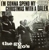 A square record cover, with the text "I'M GONNA SPEND MY CHRISTMAS WITH A DALEK" and the label "ORIOLE" (smaller) above a photograph showing a young woman and four young men in 1960s dress smiling and laughing at a grey Dalek on an urban street. The white text "the go-go's" is superimposed on the lower left quadrant of the photograph.