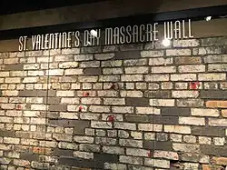 A brick wall is shown, marked and scarred. Several red circles are present around indentations caused by bullet holes