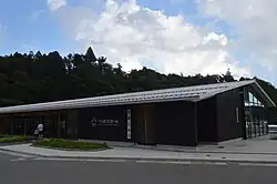 One storey long brown building with a grey sloped roof