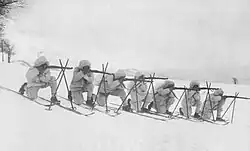 Imperial German soldiers with skies and snow camouflage air their rifles 1916