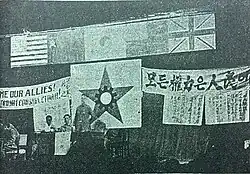 Grainy photo of a meeting with flags and banners