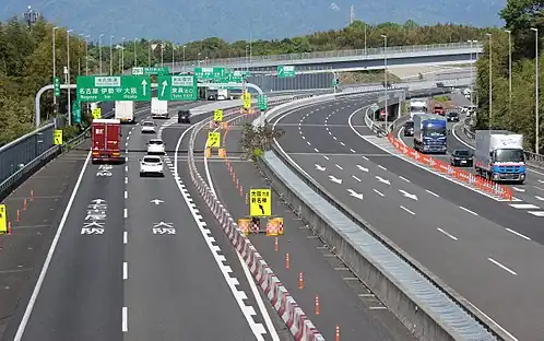 A group of green-coloured directional signs on a Japanese expressway