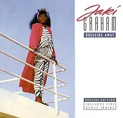 Graham stands, sideways, behind the railings of a yacht, facing the camera