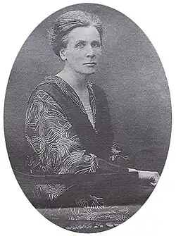 B&W oval portrait of a middle-aged seated woman wearing a patterned blouse with dark collar, her hair in an up-do