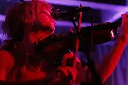 A person plays violin. They're lit with red light.