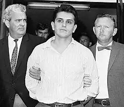 Black and white photo of Patler, surrounded by two detectives