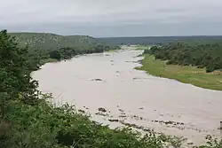 Photograph of a winding river bounded on each side by hills and greenery.