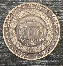 A bronze medal, bearing the legends, "BATTLE OF BENNINGTON" and "1777-1927" and 14 stars. This surrounds a wreath with ribbons with the names of battle participants such as "ALLEN". Within the wreath is a building, and the inscription "FAY'S TAVERN".