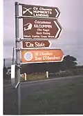 Signpost on the Lacken Road showing variant Irish spelling